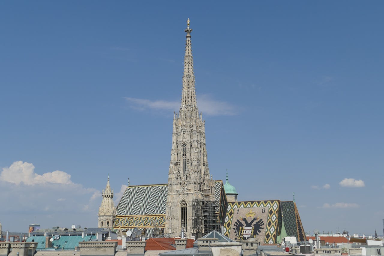 contact-bg A view of St. Stephen's Cathedral in Vienna with a clear blue sky, showcasing Gothic architecture.
